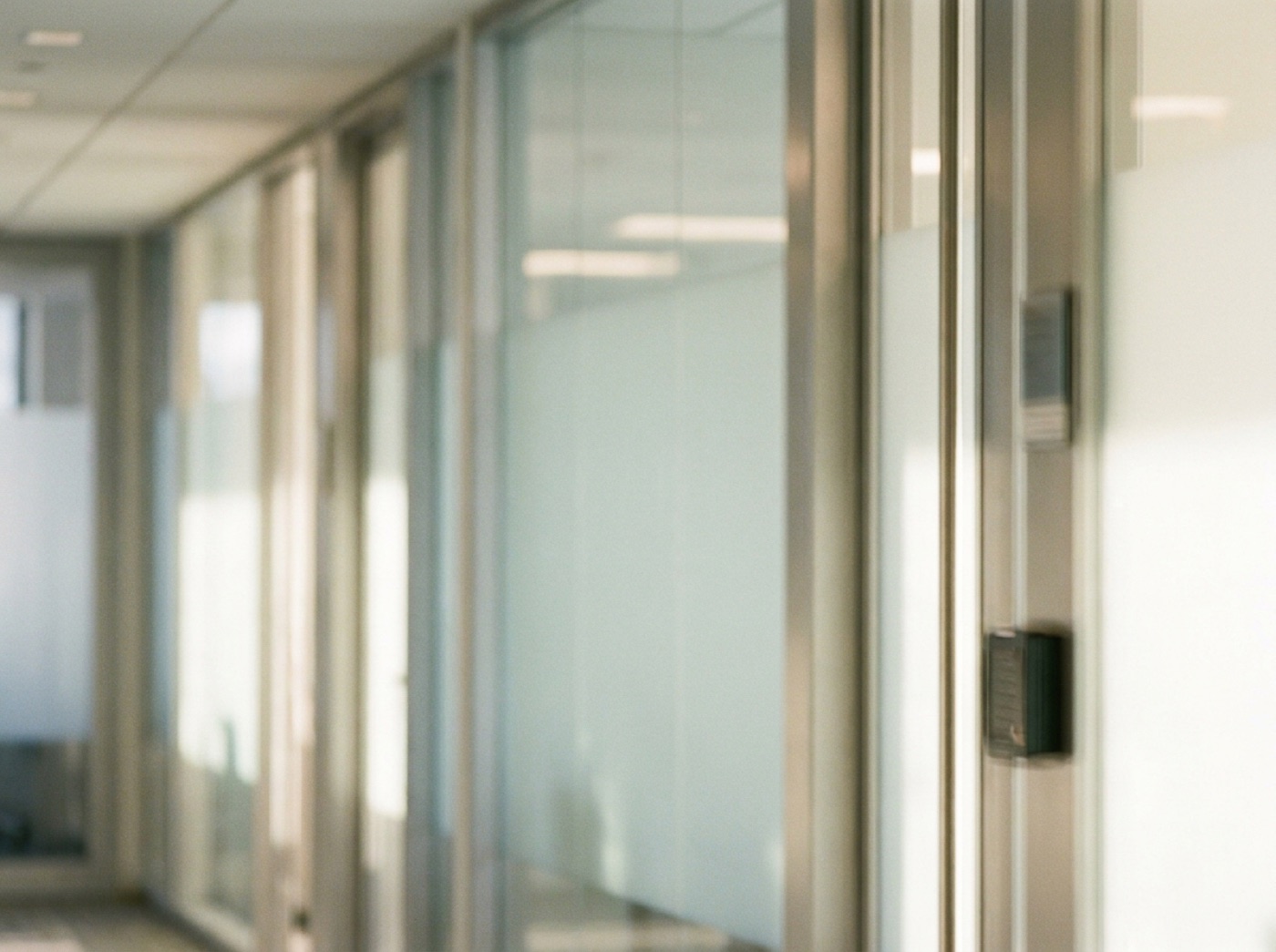 A bright office corridor with glass doors and a keycard reader