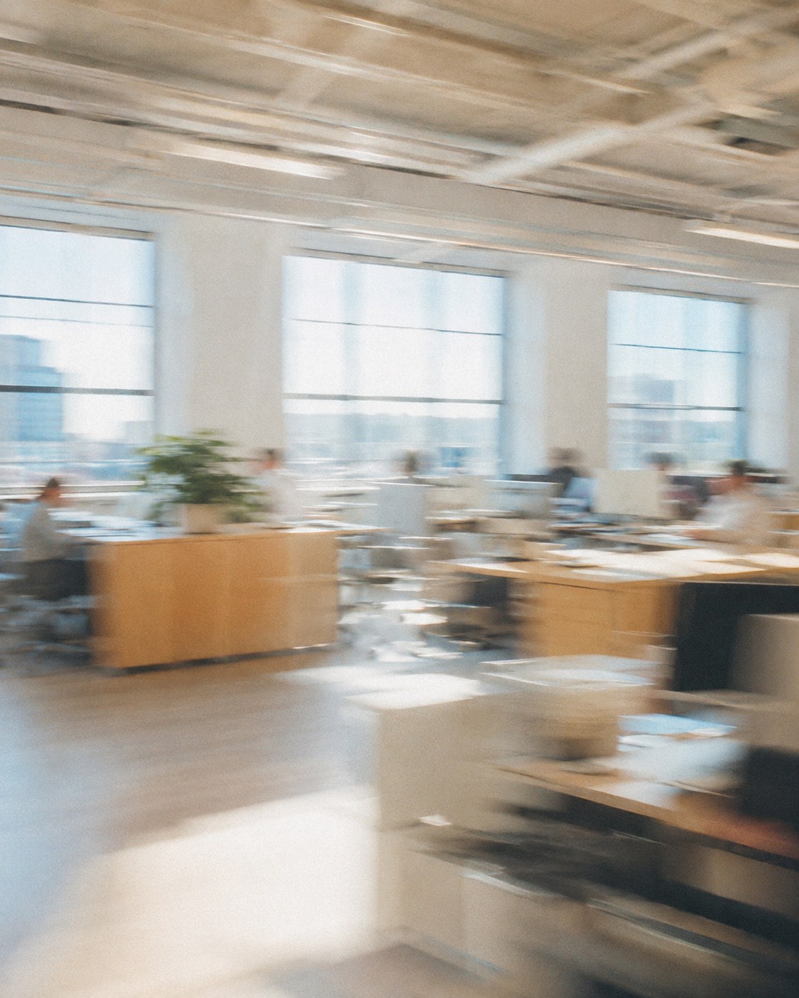 Blurred photograph of a person at a desk with two screens